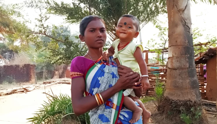 Chandrika Majhi holds her baby son outside her house in Gadadi, India.
